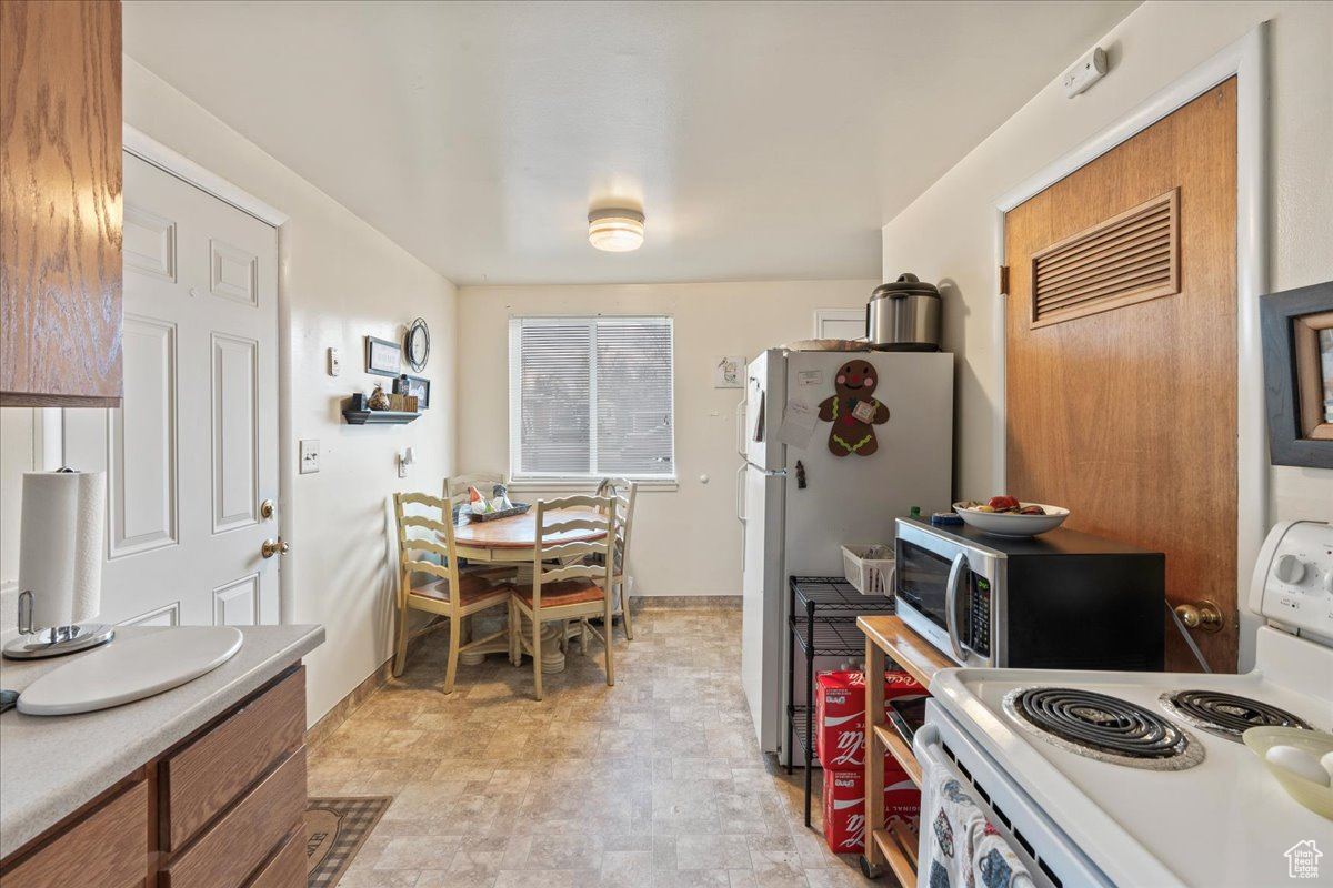 Kitchen featuring light tile floors, refrigerator, and electric range oven