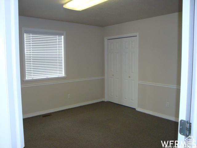 Unfurnished bedroom featuring a closet and dark colored carpet