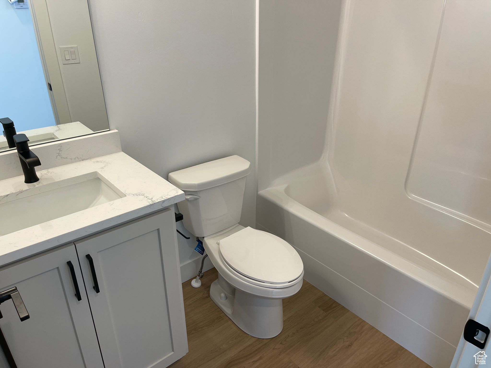 Full bathroom featuring shower / bathtub combination, vanity, wood-type flooring, and toilet