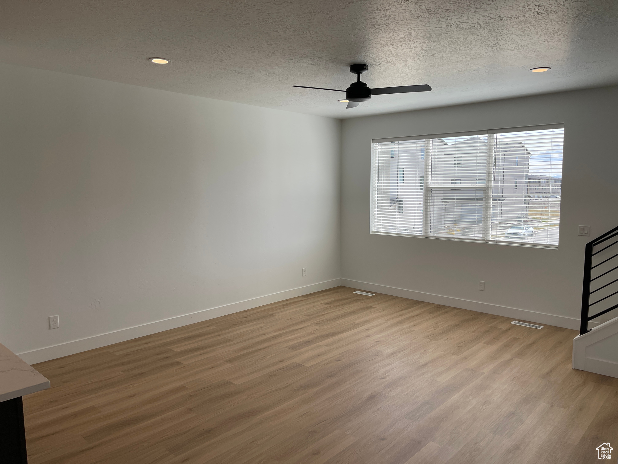 Empty room featuring light hardwood / wood-style floors, ceiling fan, and a textured ceiling
