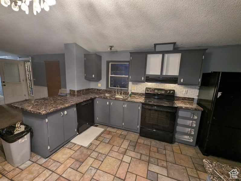 Kitchen with black appliances, sink, ventilation hood, and a textured ceiling