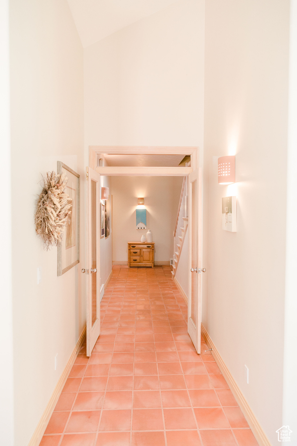 5 ft wide Hall with light tile flooring and lofted ceiling