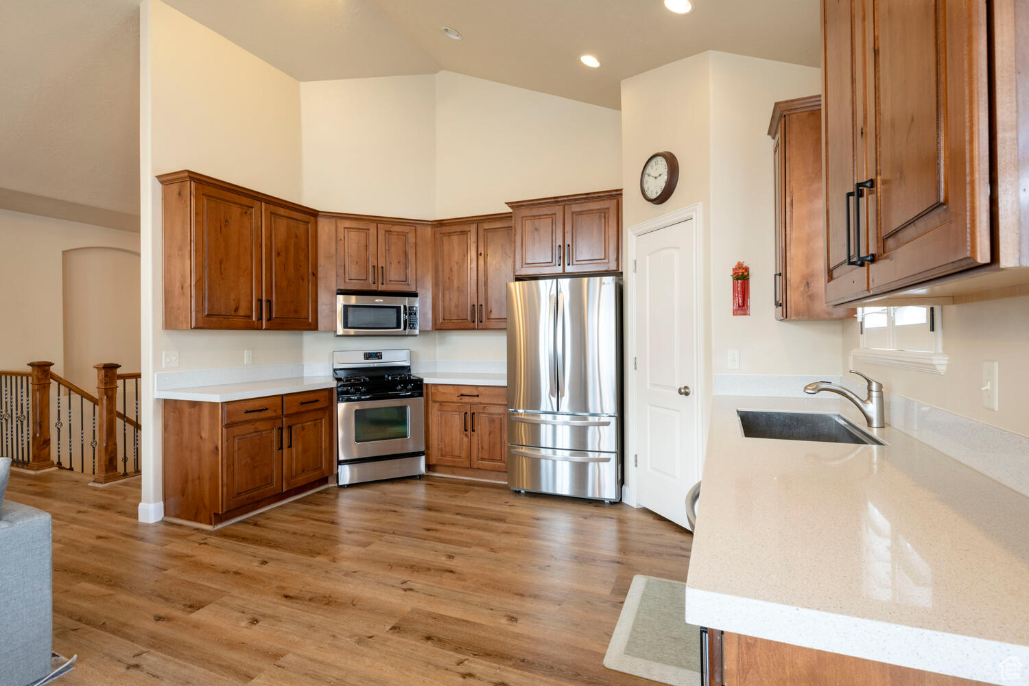 Kitchen featuring high vaulted ceiling, light hardwood / wood-style floors, sink, and stainless steel appliances
