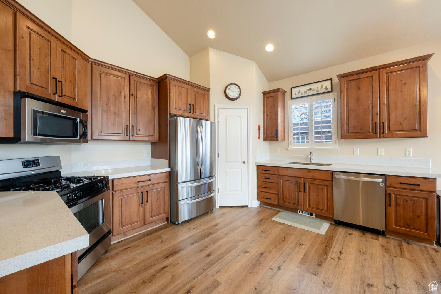 Kitchen featuring vaulted ceiling, stainless steel appliances, light hardwood / wood-style flooring, and sink