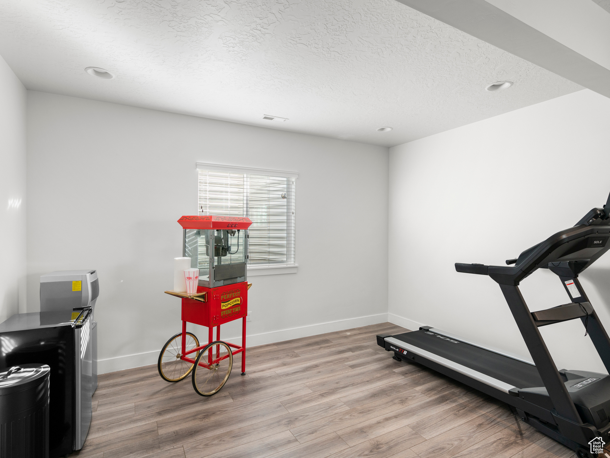 Exercise area featuring light hardwood / wood-style flooring and a textured ceiling
