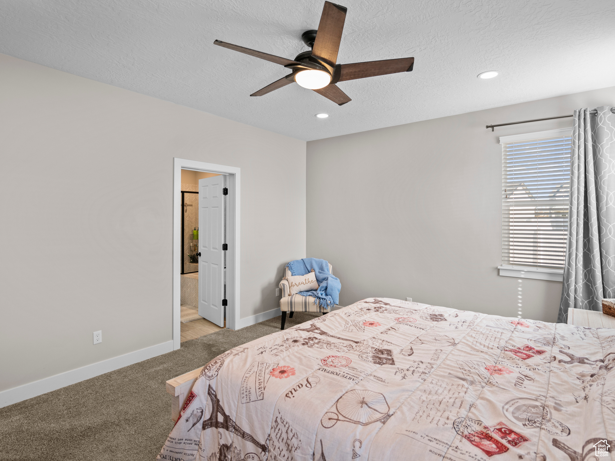 Carpeted bedroom with a textured ceiling, ceiling fan, and connected bathroom