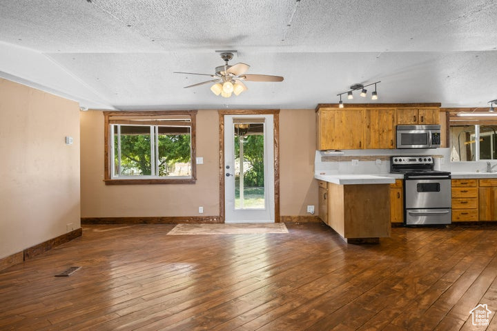 Kitchen featuring appliances with stainless steel finishes, dark hardwood / wood-style floors, ceiling fan, and a textured ceiling