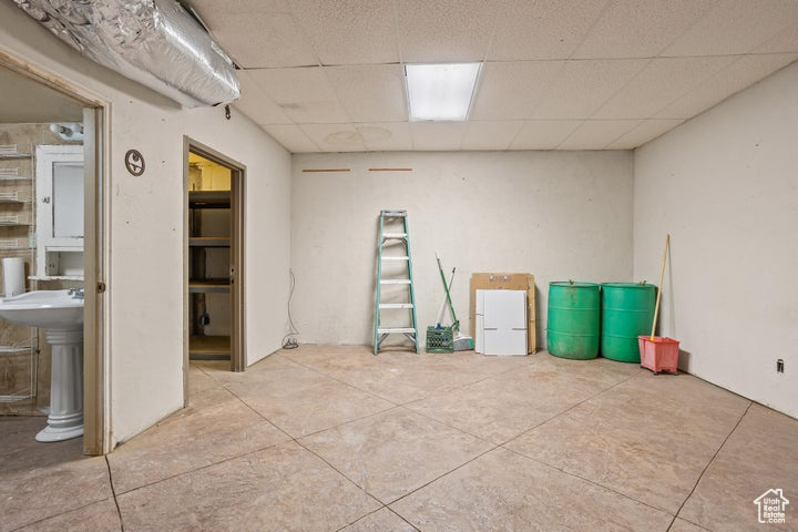 Misc room featuring sink, light tile patterned flooring, and a paneled ceiling