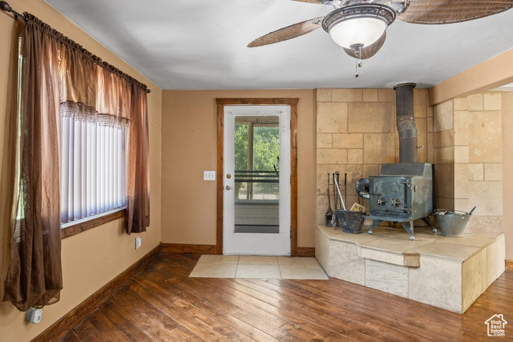 Unfurnished living room with ceiling fan, hardwood / wood-style floors, and a wood stove