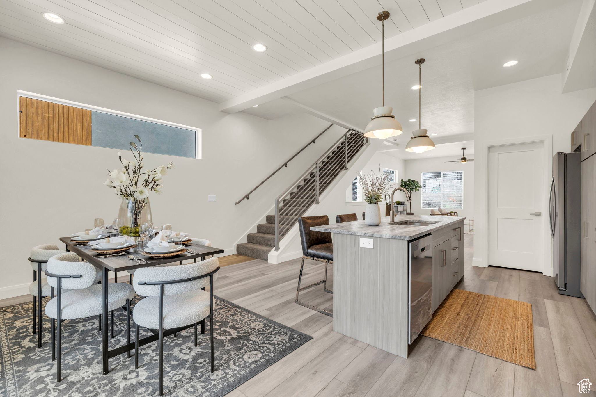 Kitchen with a kitchen island with sink, sink, pendant lighting, and light hardwood / wood-style flooring