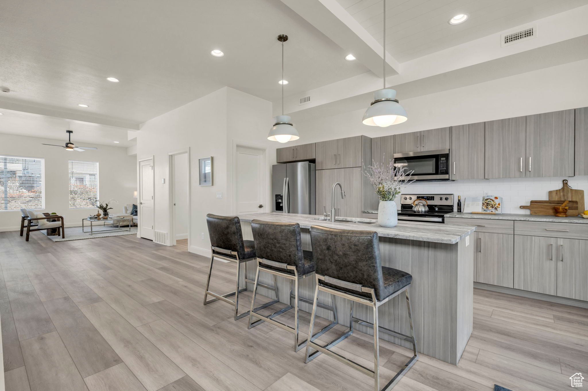 Kitchen with a kitchen bar, hanging light fixtures, ceiling fan, and stainless steel appliances