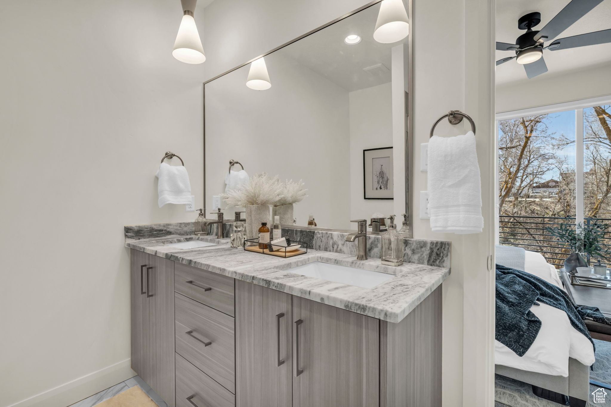 Bathroom featuring vanity with extensive cabinet space, dual sinks, and ceiling fan