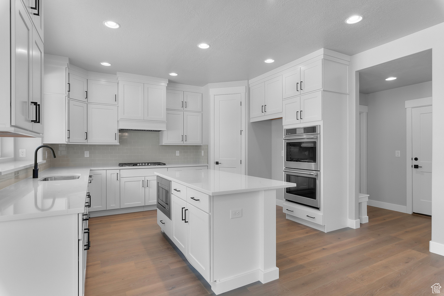 Kitchen featuring hardwood / wood-style floors, appliances with stainless steel finishes, sink, and a center island