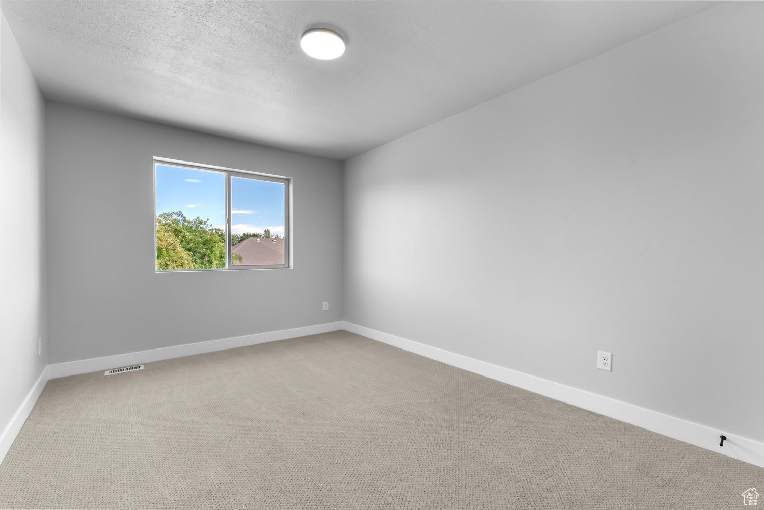 Carpeted spare room with a textured ceiling