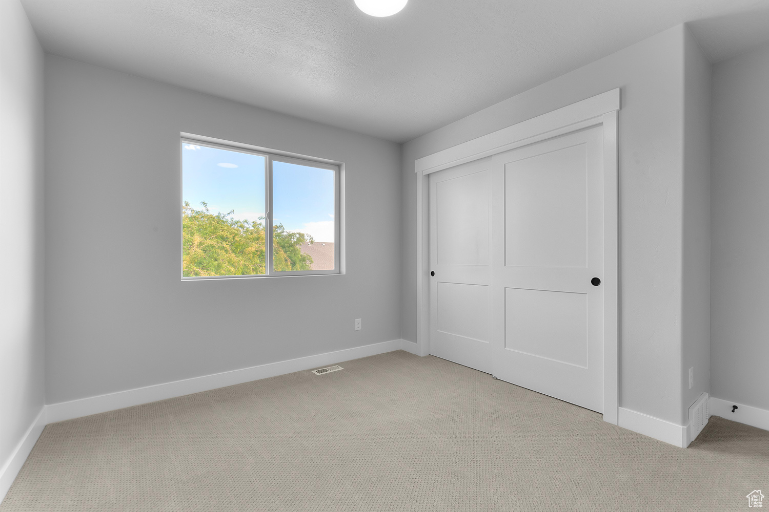 Unfurnished bedroom featuring a closet and light carpet