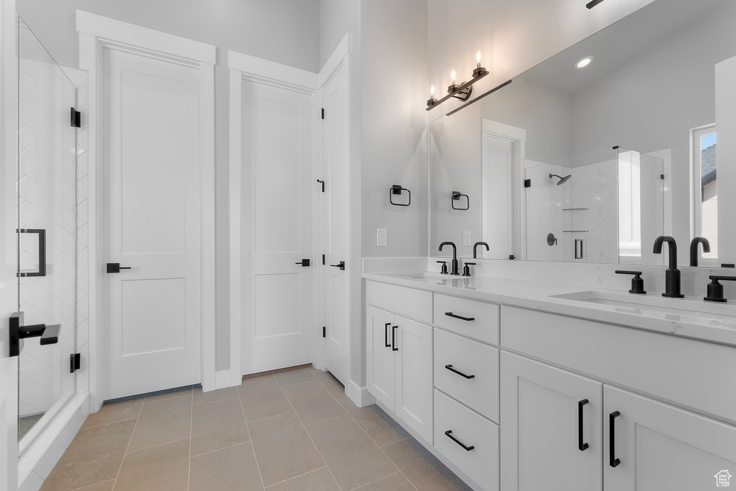 Bathroom featuring tile patterned floors, a shower with door, and vanity