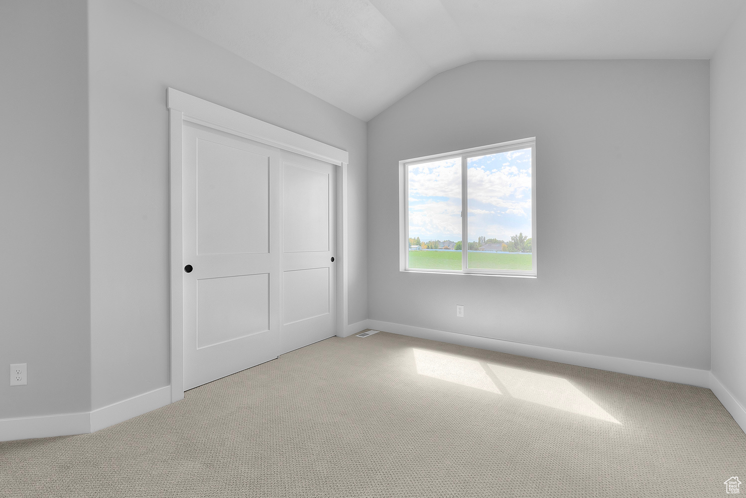 Unfurnished bedroom with a closet, lofted ceiling, and light colored carpet