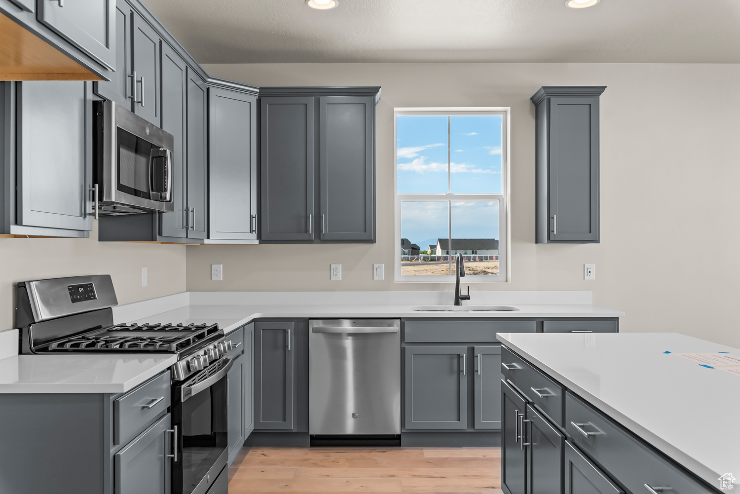 Kitchen featuring gray cabinets, appliances with stainless steel finishes, sink, and light hardwood / wood-style floors