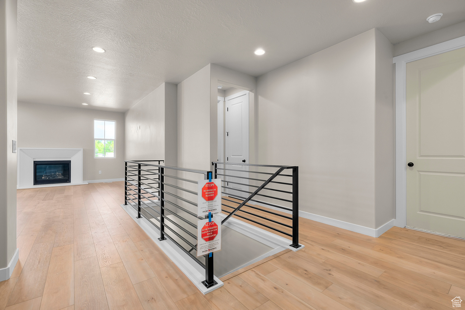 Hallway with light hardwood / wood-style flooring and a textured ceiling