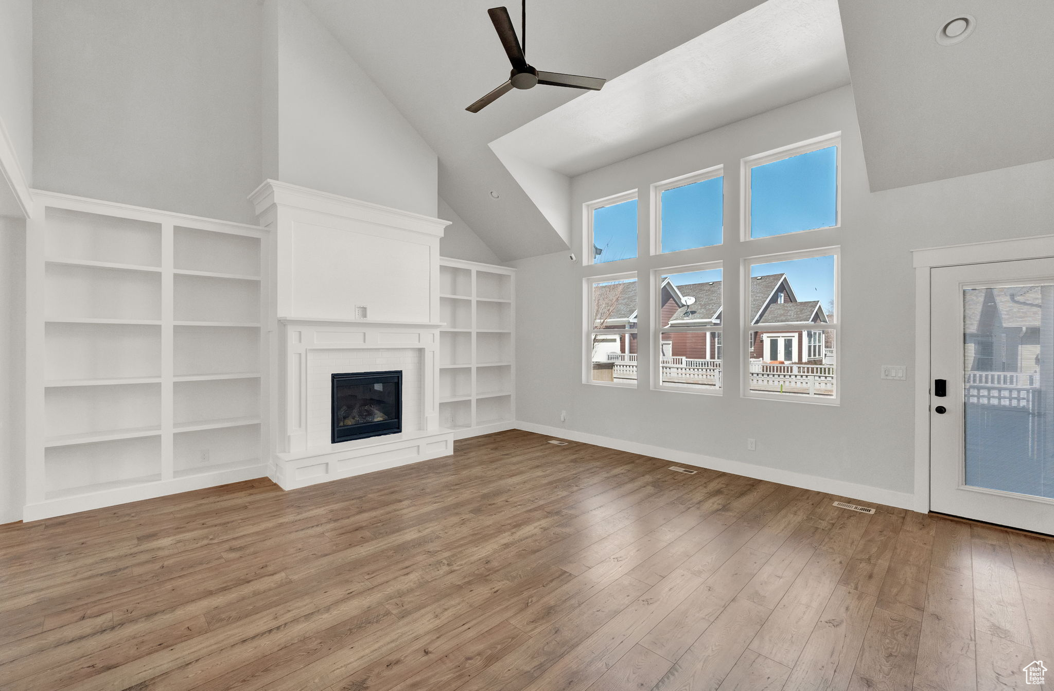 Living room with built in features, high vaulted ceiling, dark hardwood / wood-style floors, and ceiling fan