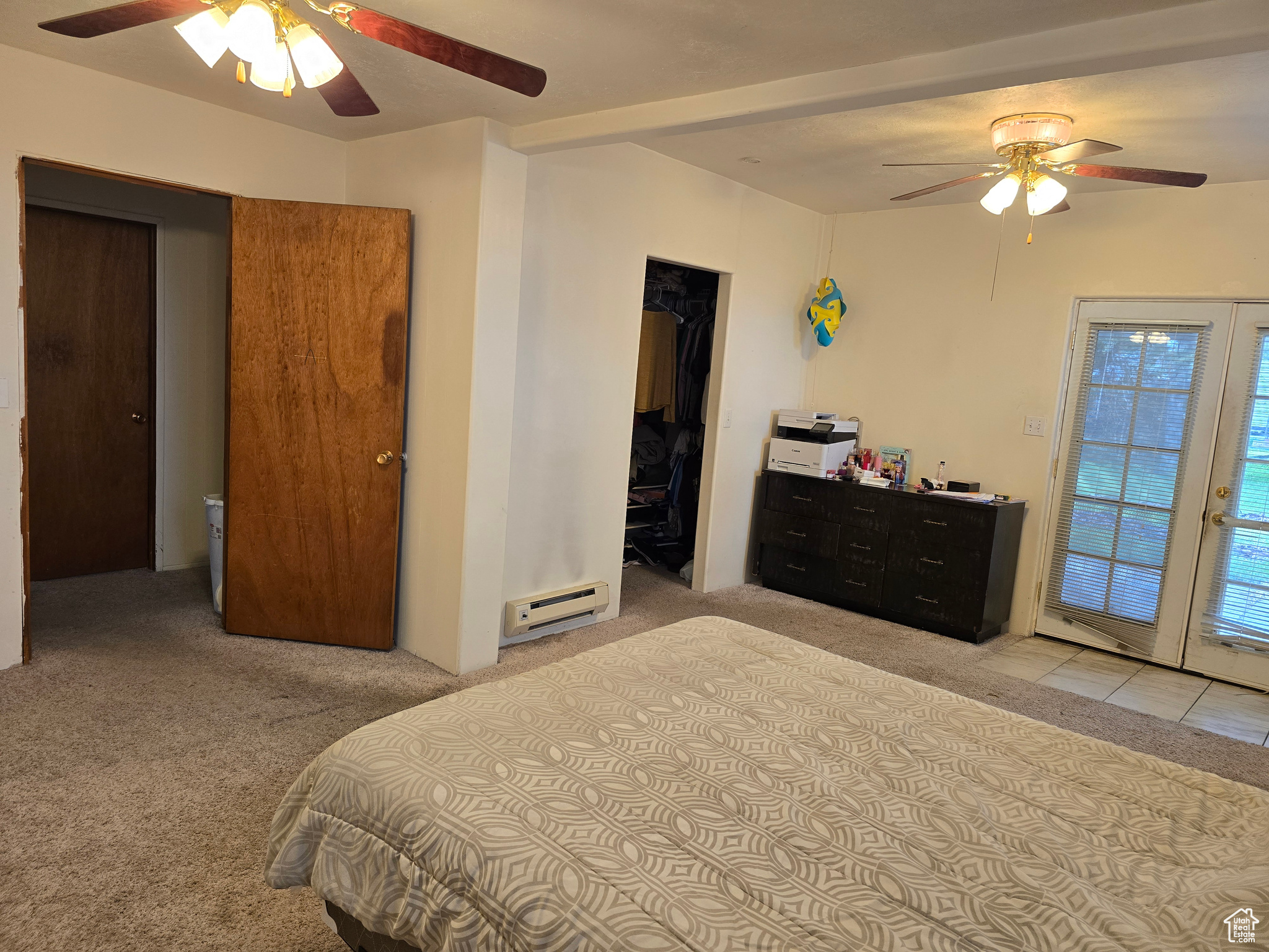 Carpeted bedroom featuring a spacious closet, access to outside, ceiling fan, and baseboard heating