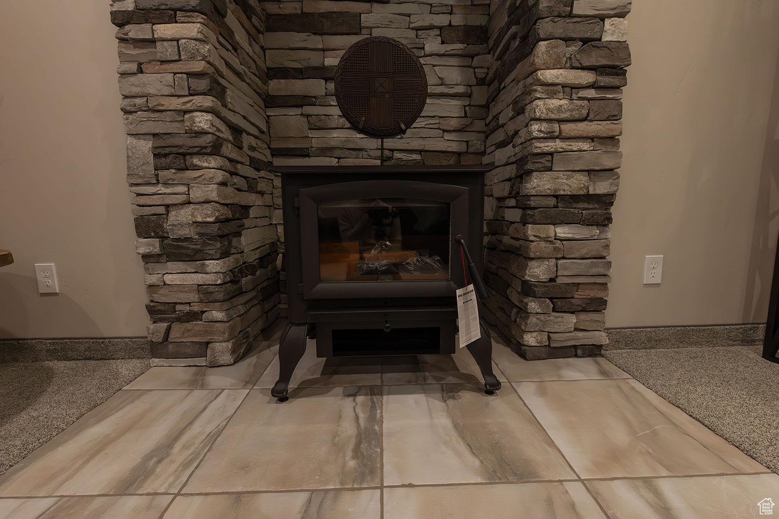 Room details with a stone fireplace and a wood stove