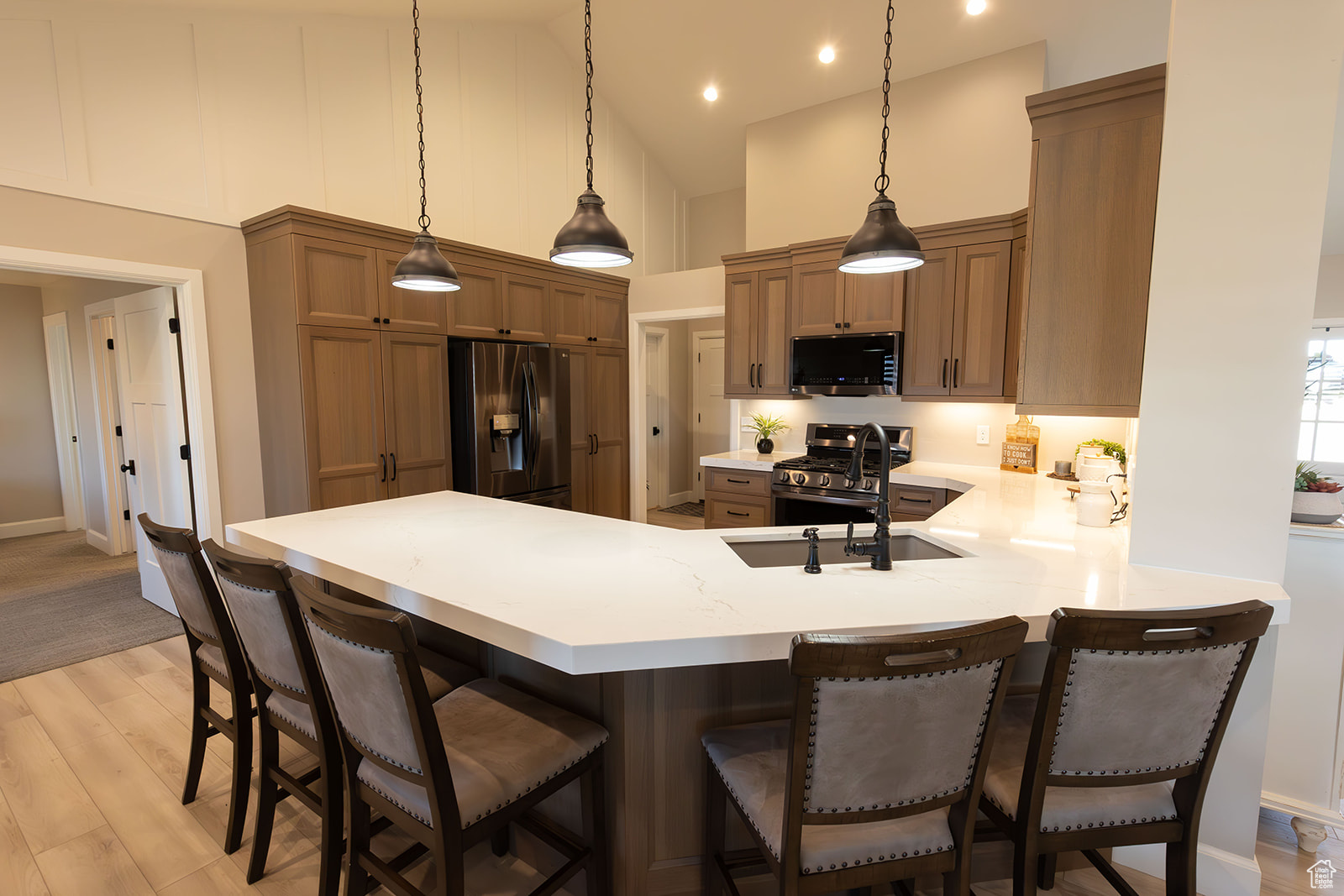 Kitchen with pendant lighting, light wood-type flooring, a breakfast bar area, and appliances with stainless steel finishes