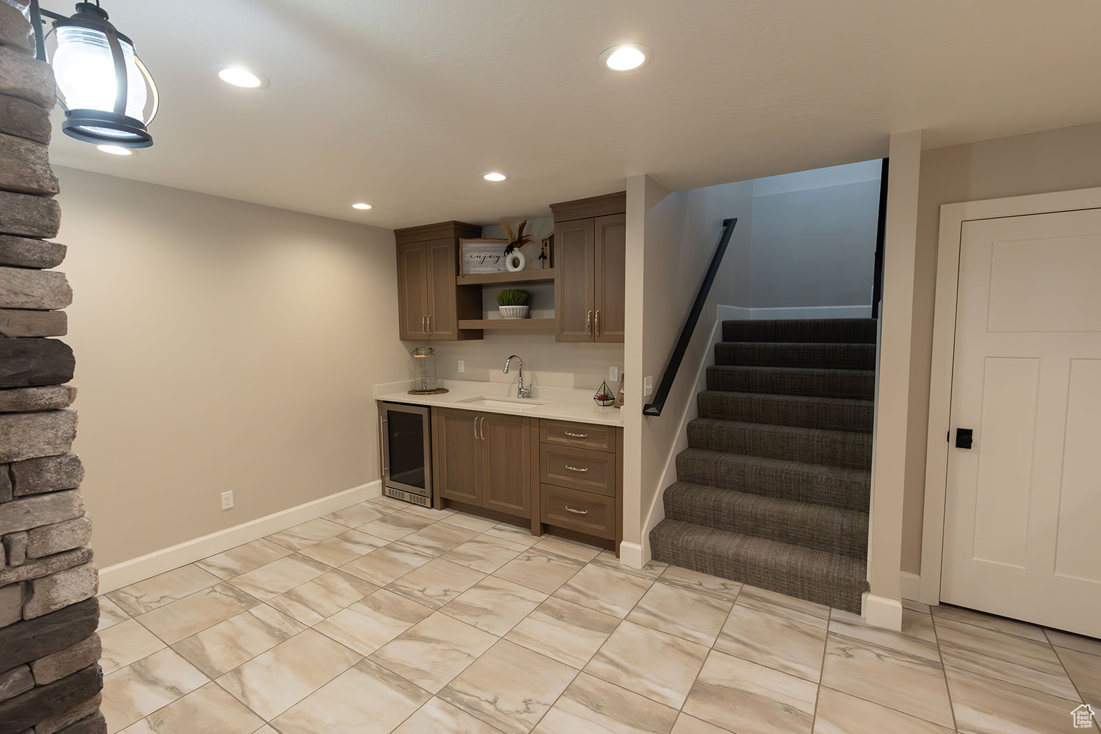 Kitchen with dark brown cabinetry, beverage cooler, light tile floors, and sink