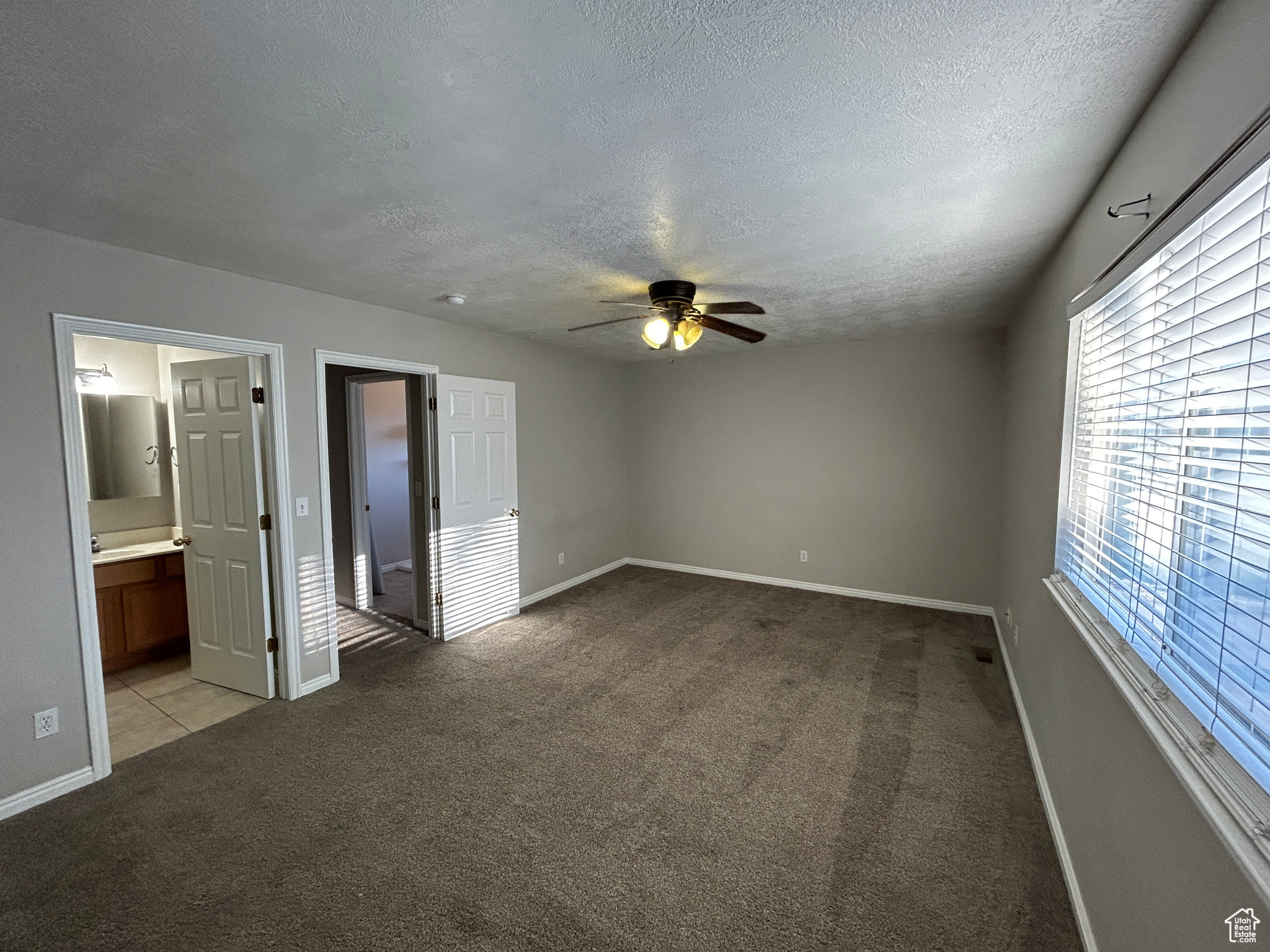 Master Bedroom with a textured ceiling, ceiling fan, and light colored carpet