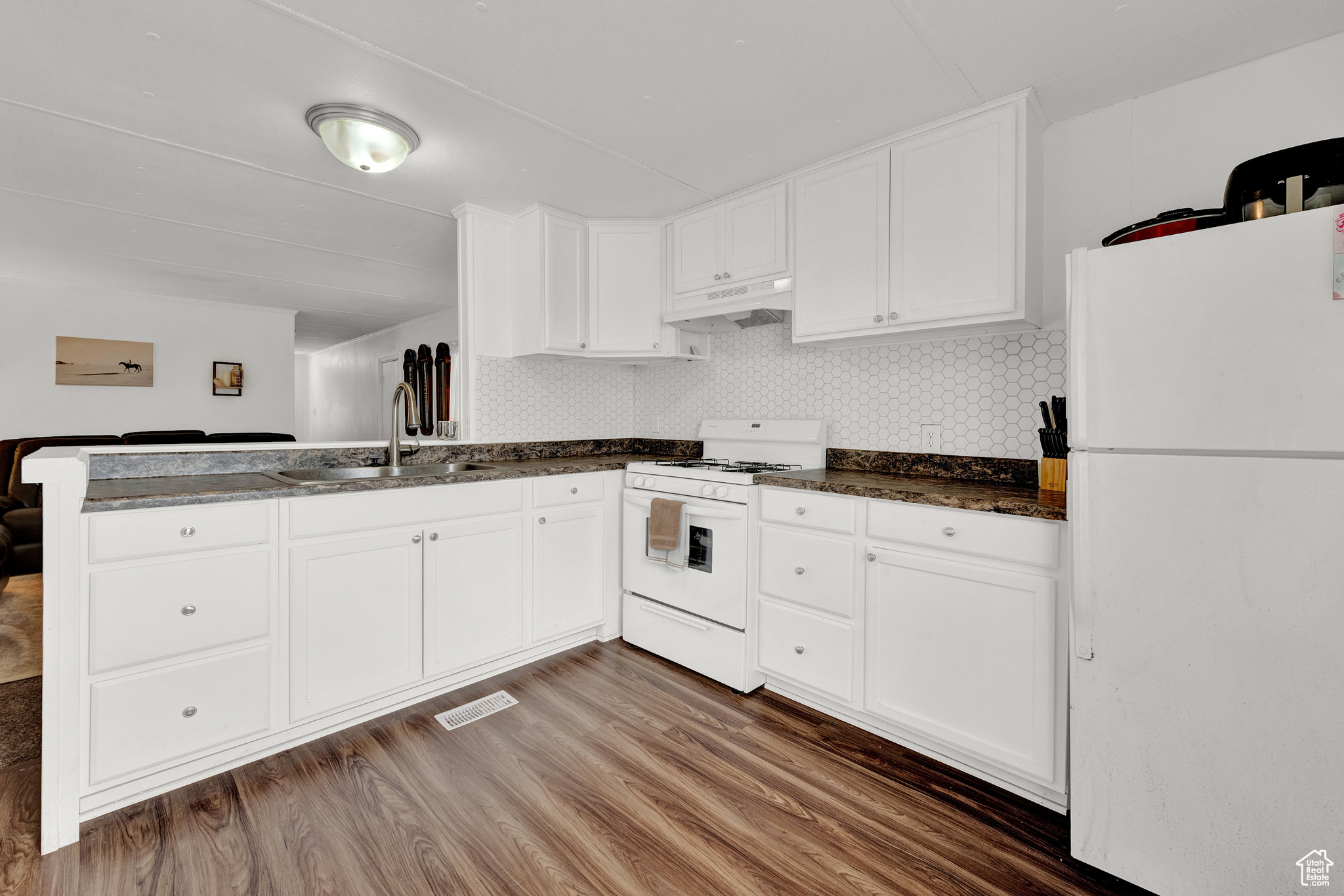 Kitchen with white cabinetry, white appliances, dark hardwood / wood-style floors, and sink