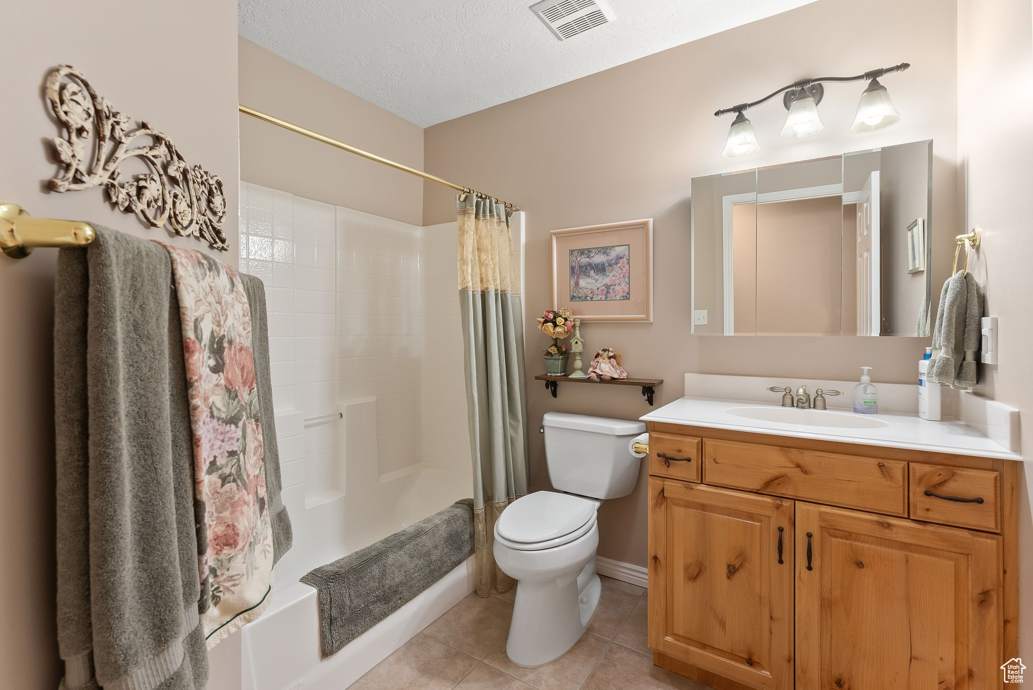 Full bathroom featuring toilet, tile flooring, a textured ceiling, vanity, and shower / bathtub combination with curtain