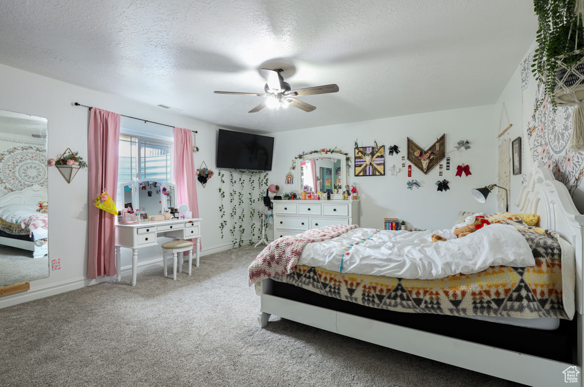 Bedroom featuring light carpet, ceiling fan, and a textured ceiling