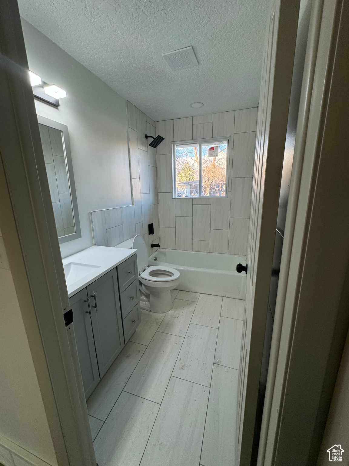 Full bathroom featuring vanity, tiled shower / bath, tile flooring, a textured ceiling, and toilet