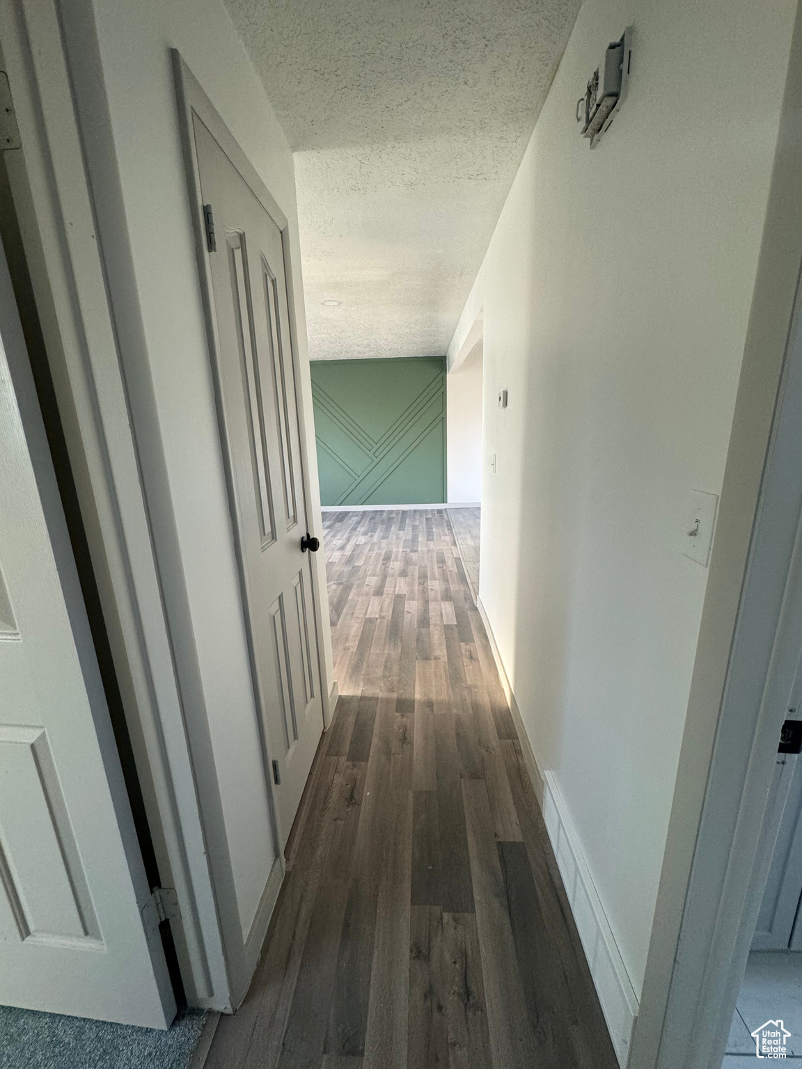 Hallway featuring a textured ceiling and dark hardwood / wood-style floors