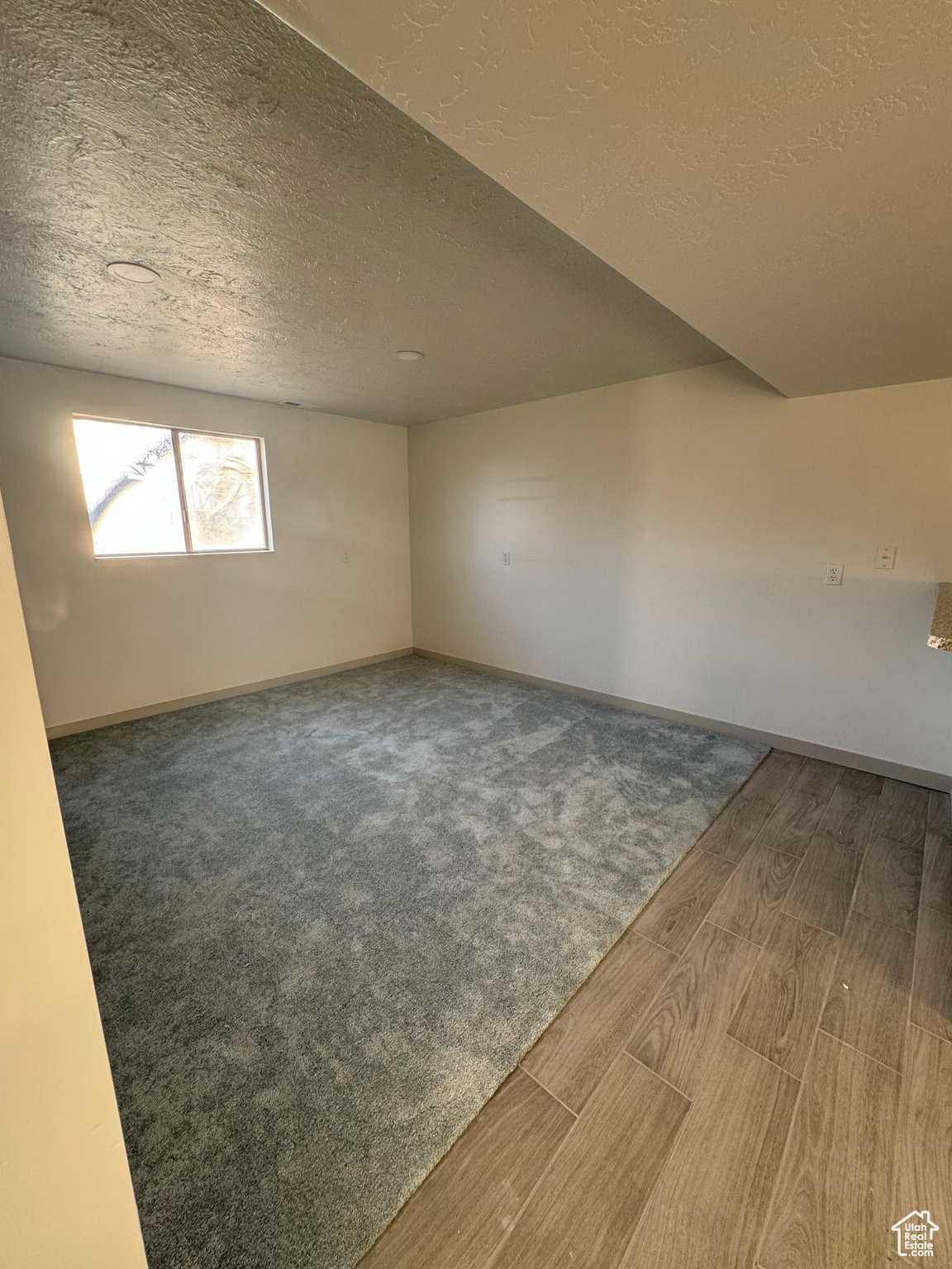 Spare room with a textured ceiling and dark hardwood / wood-style floors