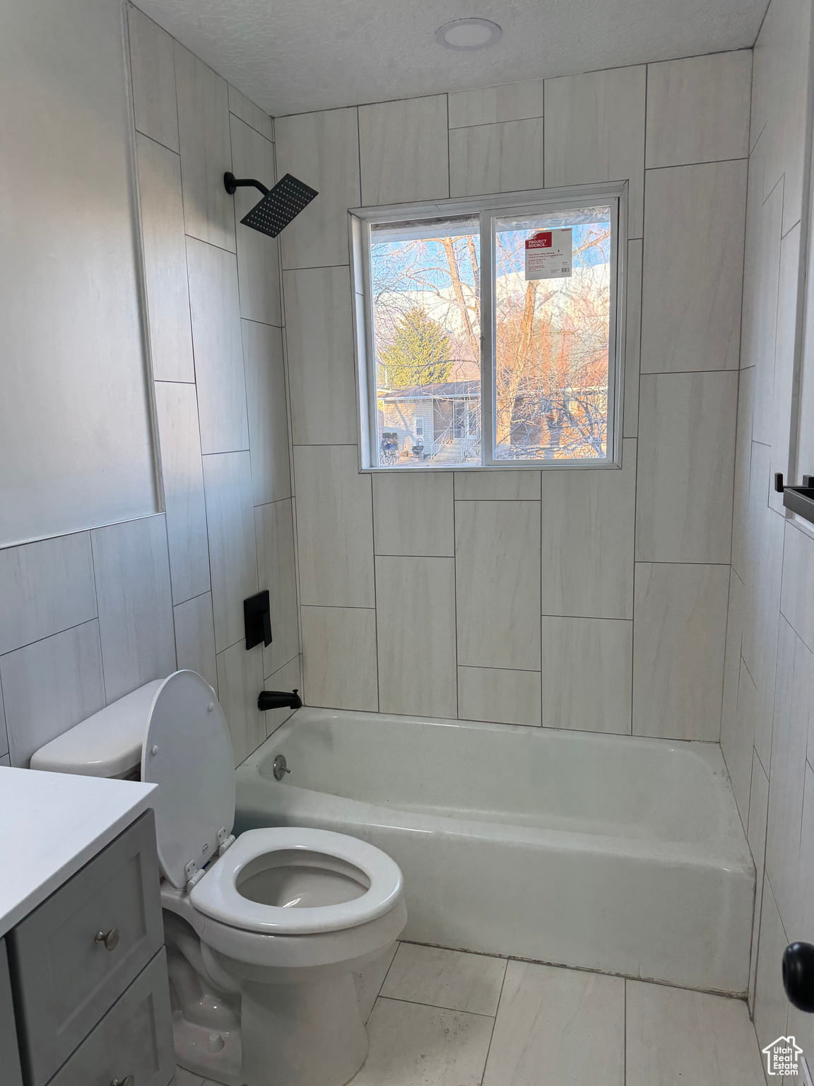 Full bathroom featuring tiled shower / bath, toilet, tile floors, and vanity