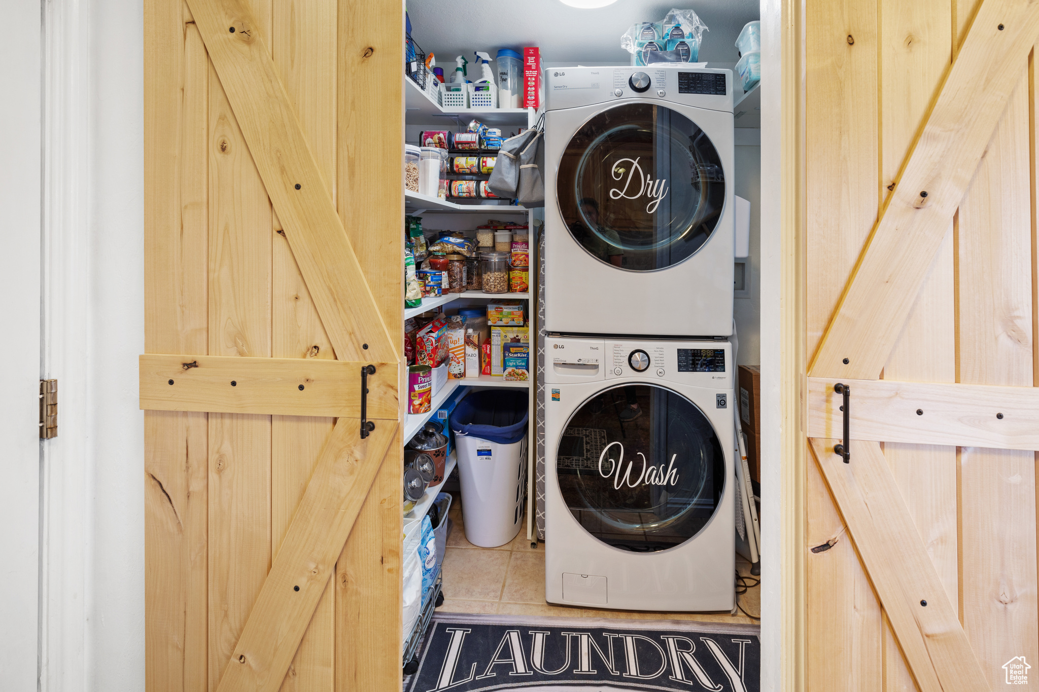 Washroom featuring stacked washer and dryer and light tile flooring