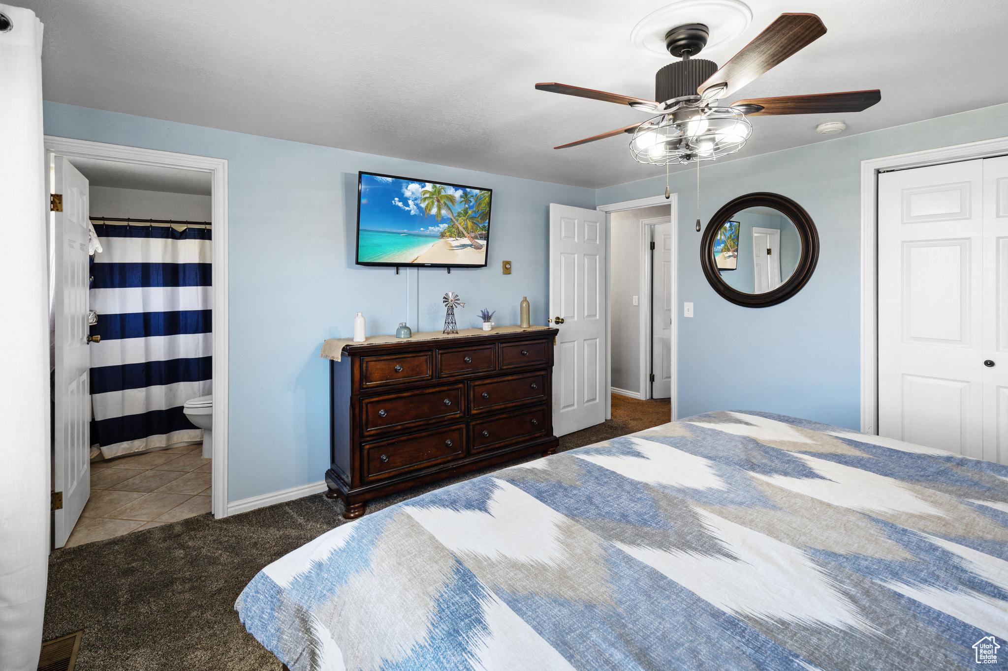 Bedroom featuring dark carpet, connected bathroom, a closet, and ceiling fan