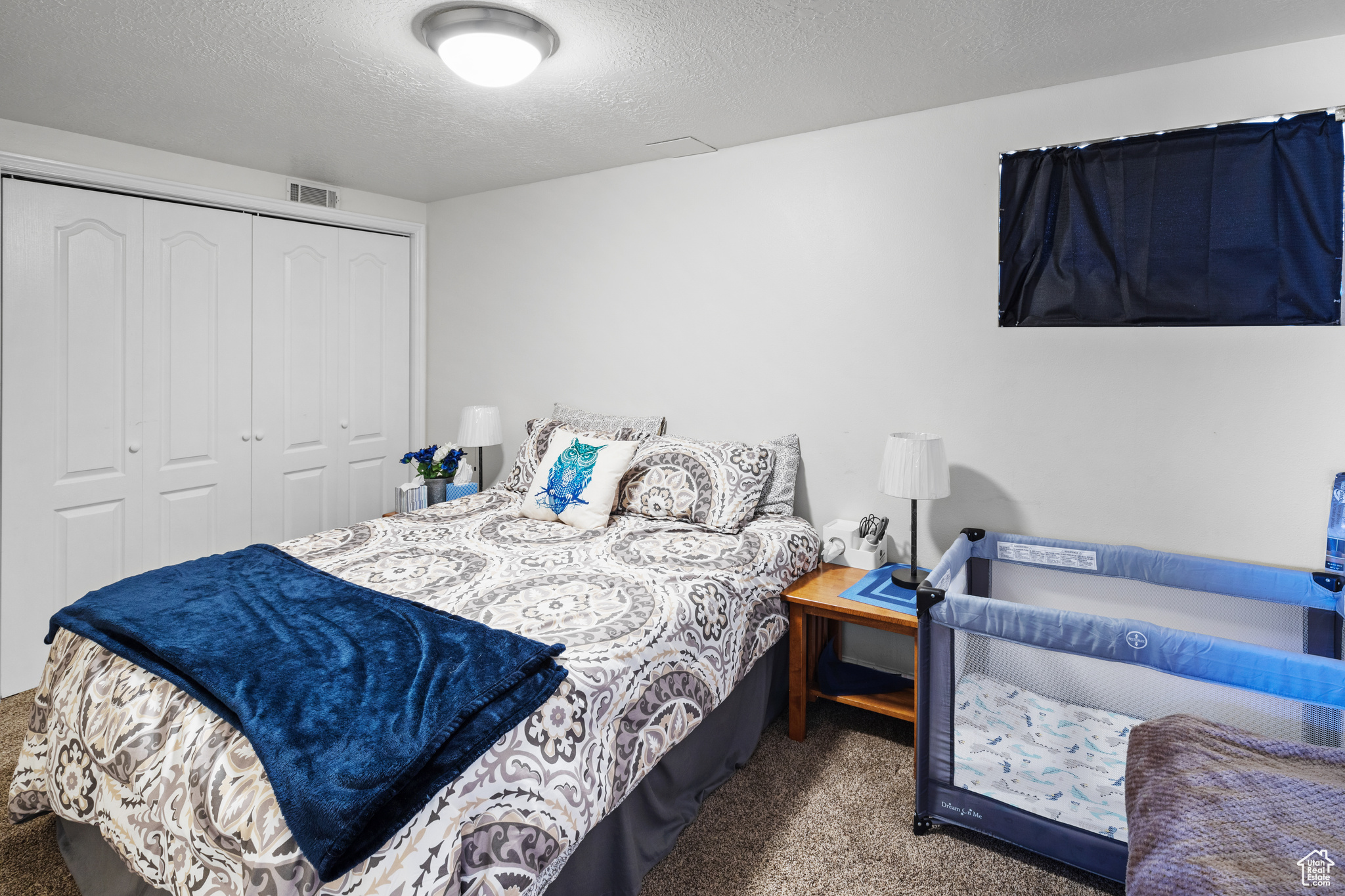 Bedroom with dark carpet, a closet, and a textured ceiling