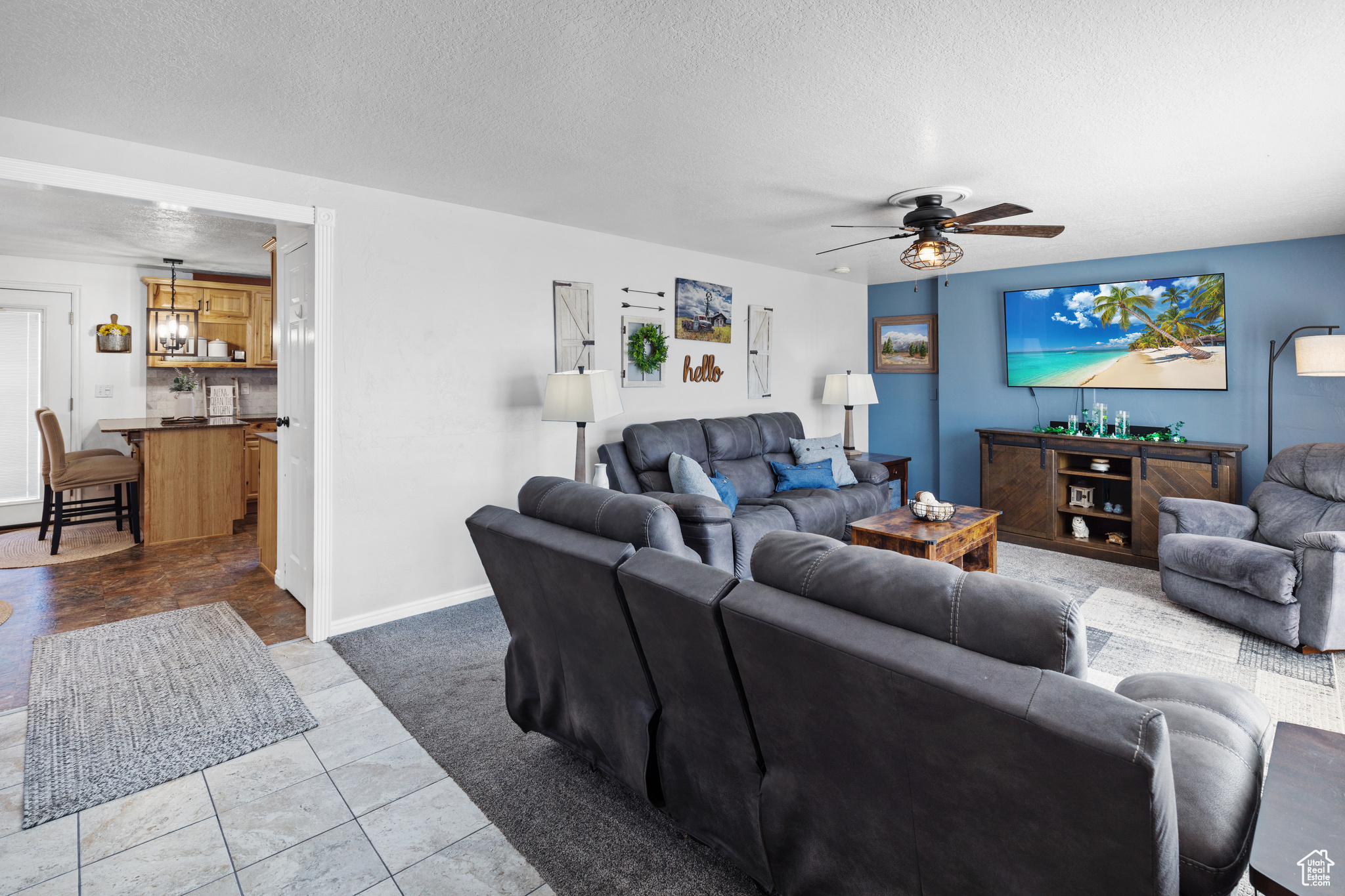 Tiled living room featuring ceiling fan and a textured ceiling