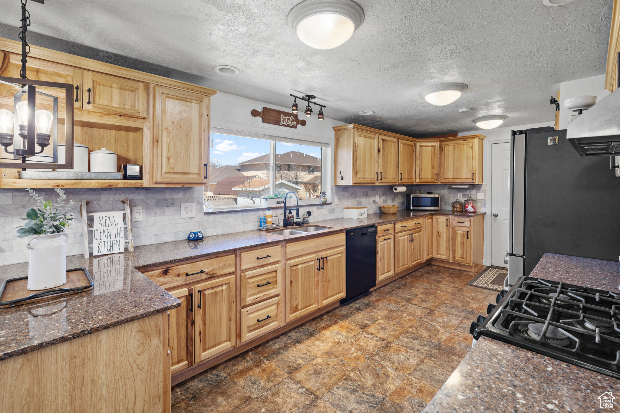 Kitchen with appliances with stainless steel finishes, dark tile flooring, and tasteful backsplash