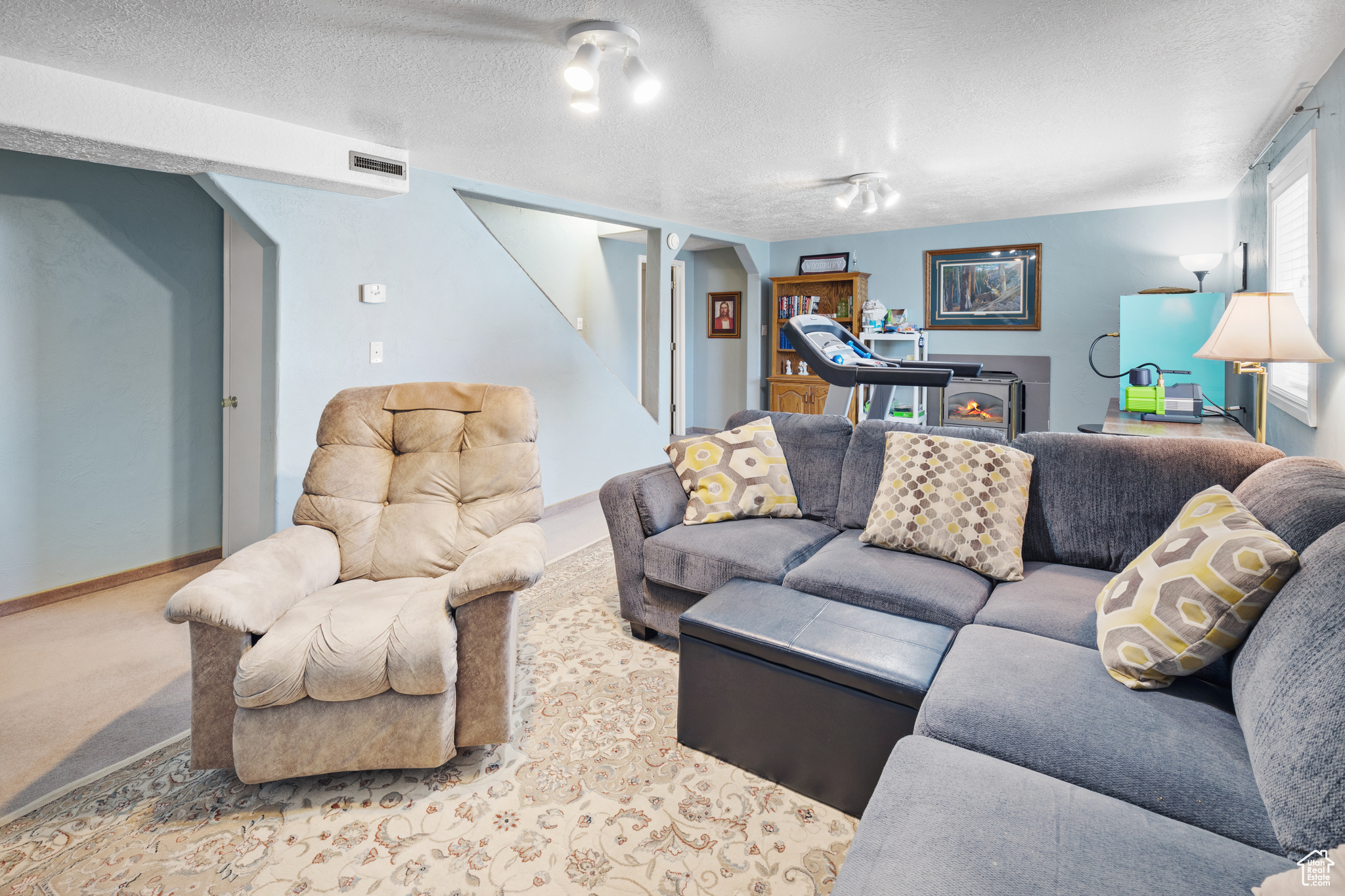 Carpeted living room with a wood stove and a textured ceiling