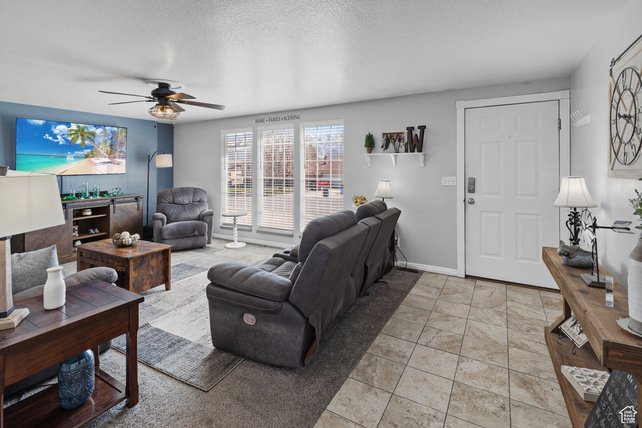 Tiled living room with ceiling fan and a textured ceiling