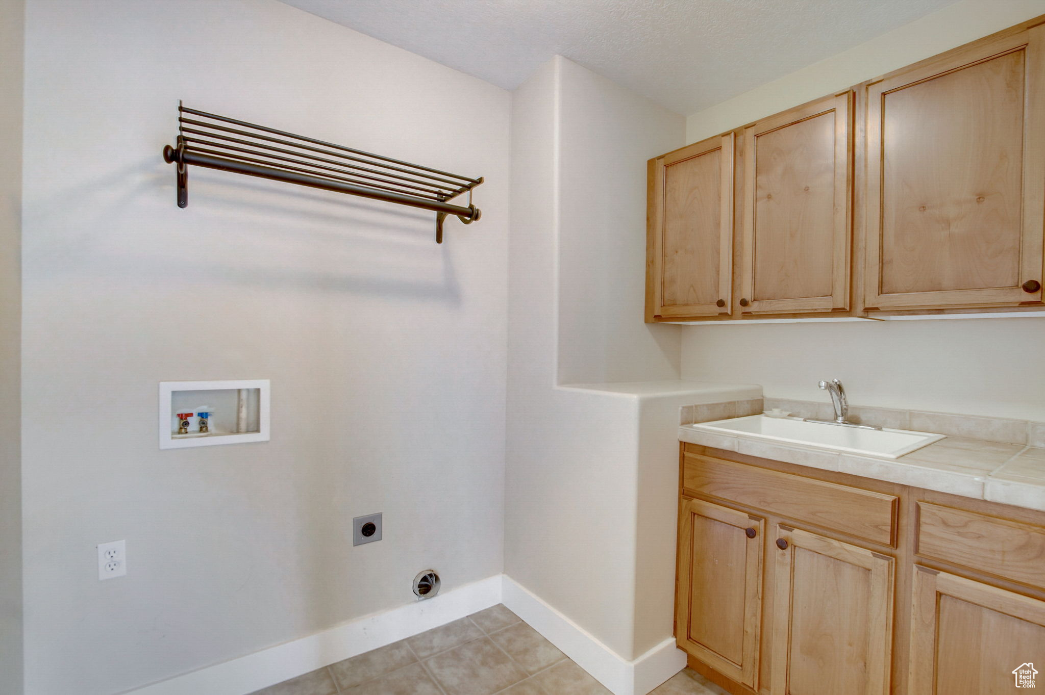 Washroom featuring electric dryer hookup, light tile floors, sink, cabinets, and hookup for a washing machine