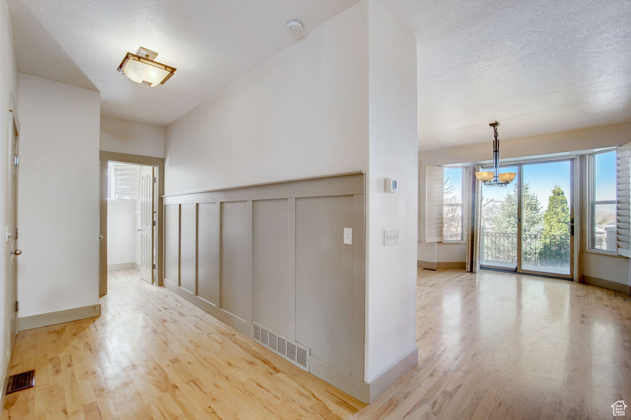 Hallway featuring a notable chandelier, a textured ceiling, and light hardwood / wood-style floors