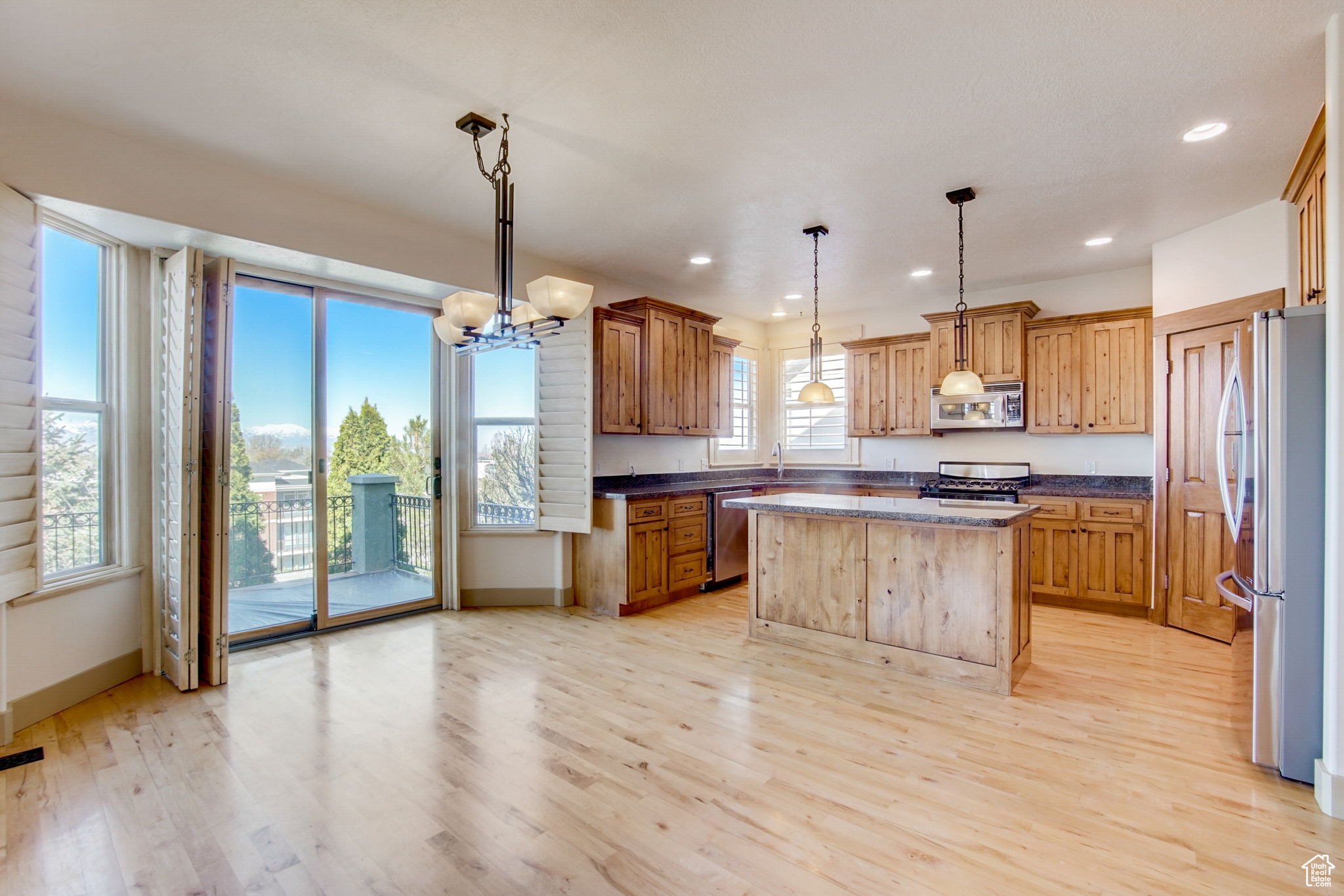 Kitchen with a notable chandelier, a kitchen island, light hardwood / wood-style flooring, and stainless steel appliances