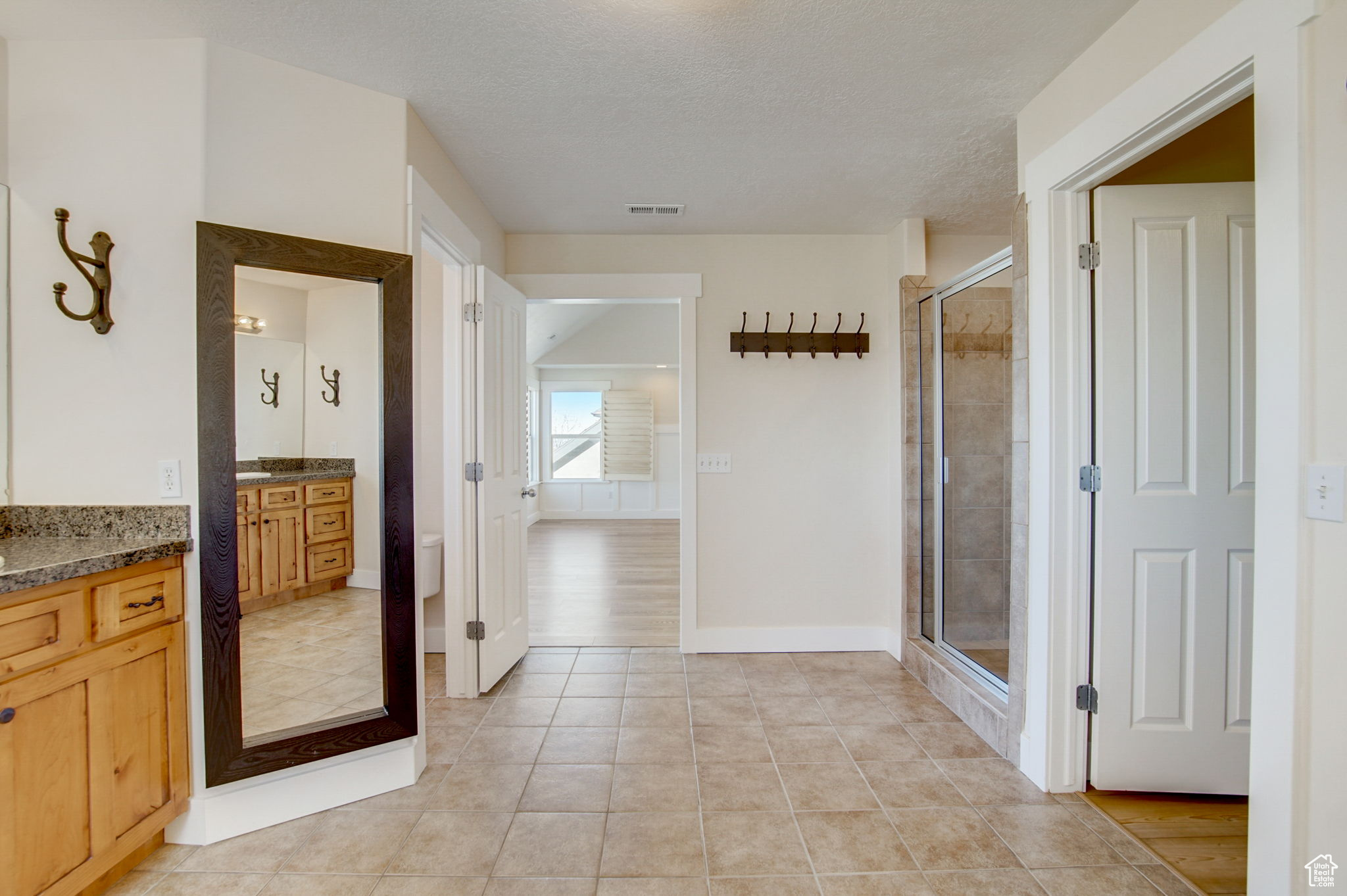 Bathroom featuring toilet, a shower with shower door, tile flooring, a textured ceiling, and vanity