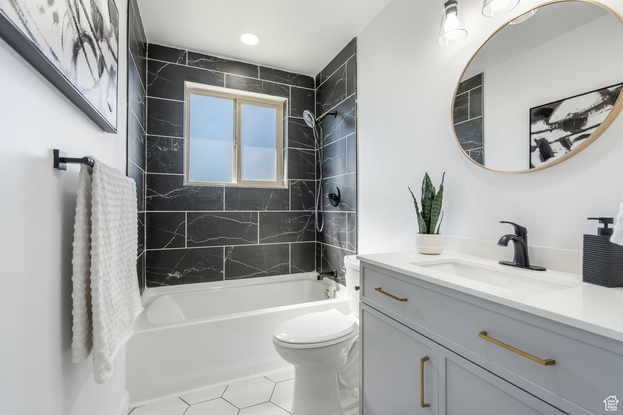 Full bathroom with tiled shower / bath combo, tile flooring, toilet, and large vanity