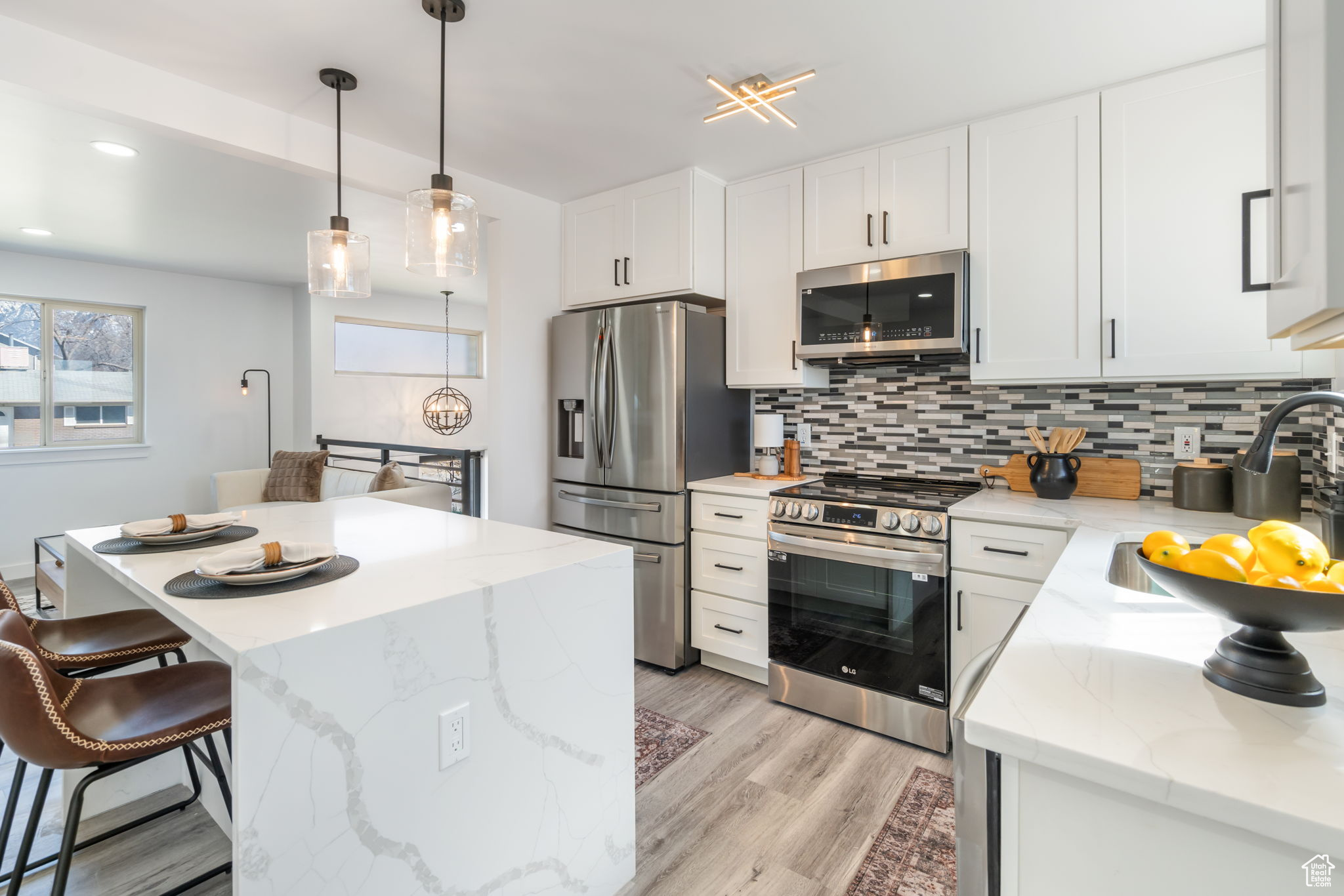 Kitchen featuring tasteful backsplash, stainless steel appliances, white cabinetry, and light wood-type flooring