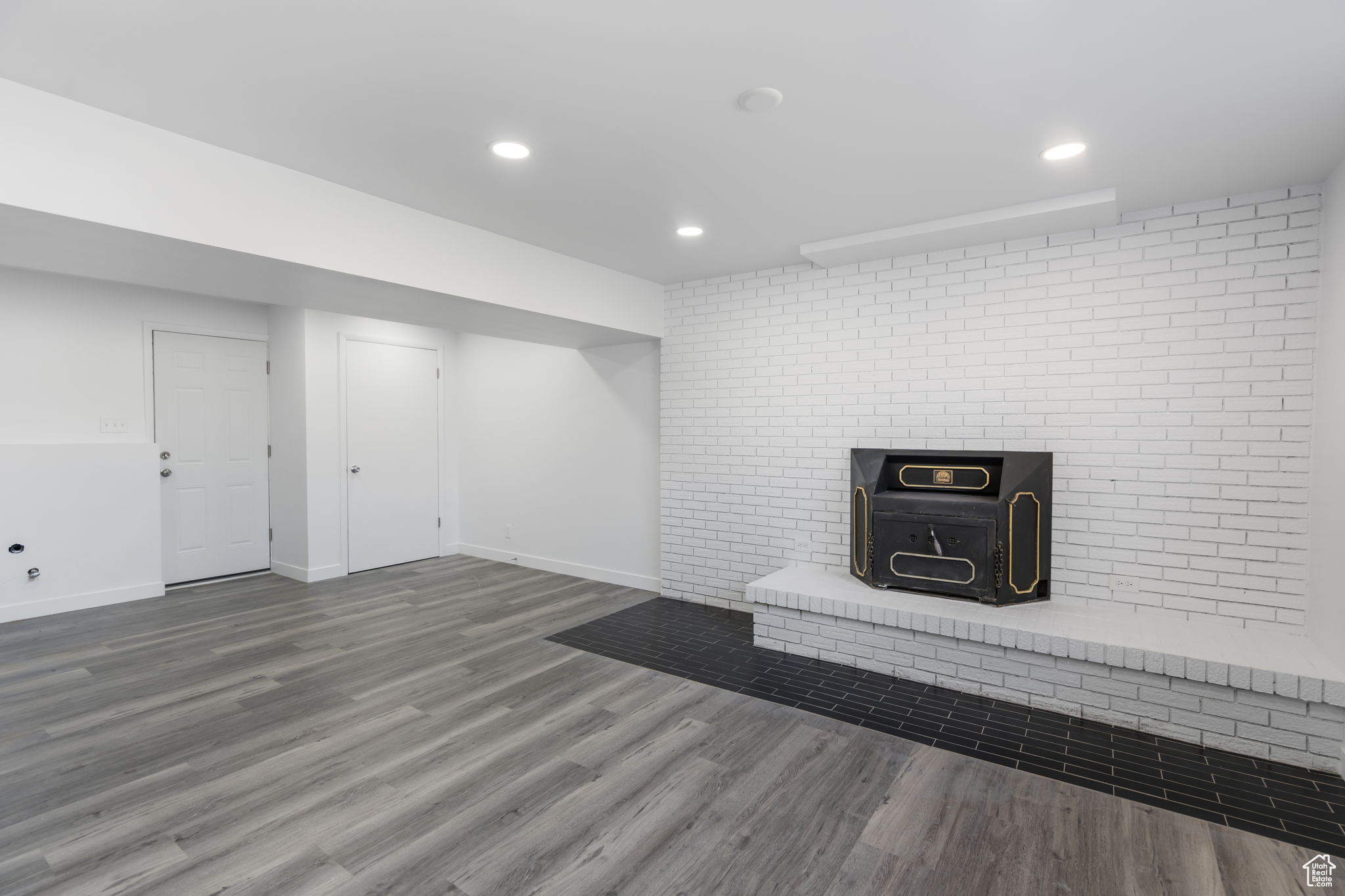 Basement featuring a wood stove, brick wall, and hardwood / wood-style floors